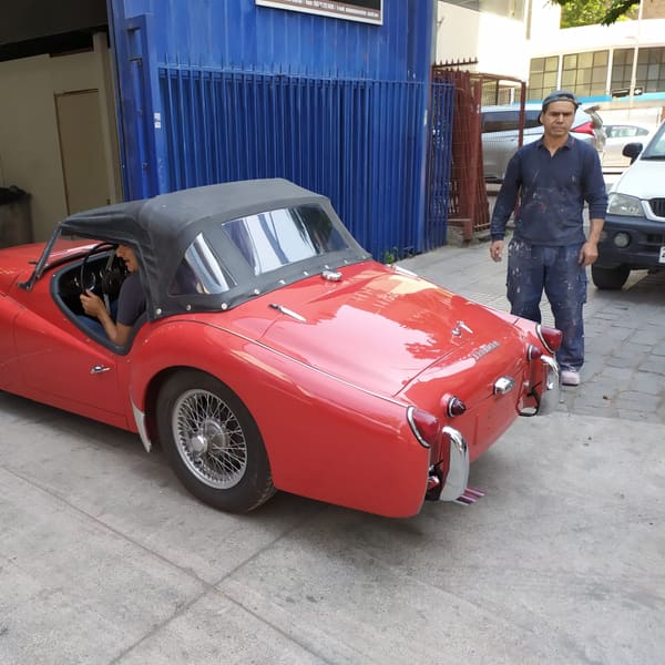 Técnico del taller junto a un Triumph TR3 en restauración